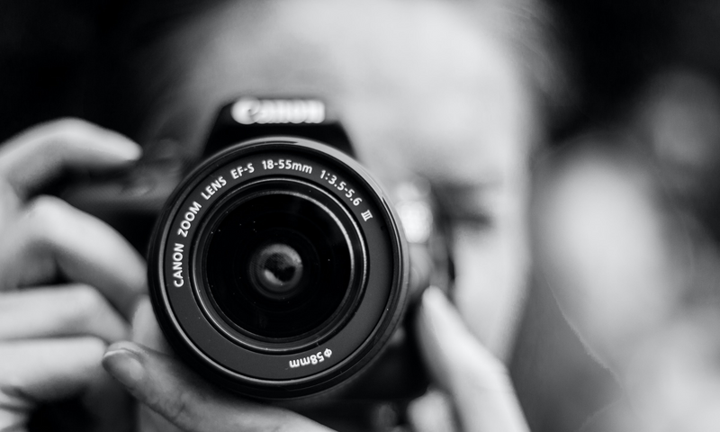 Blurry Black & White image of woman with professional camera.
